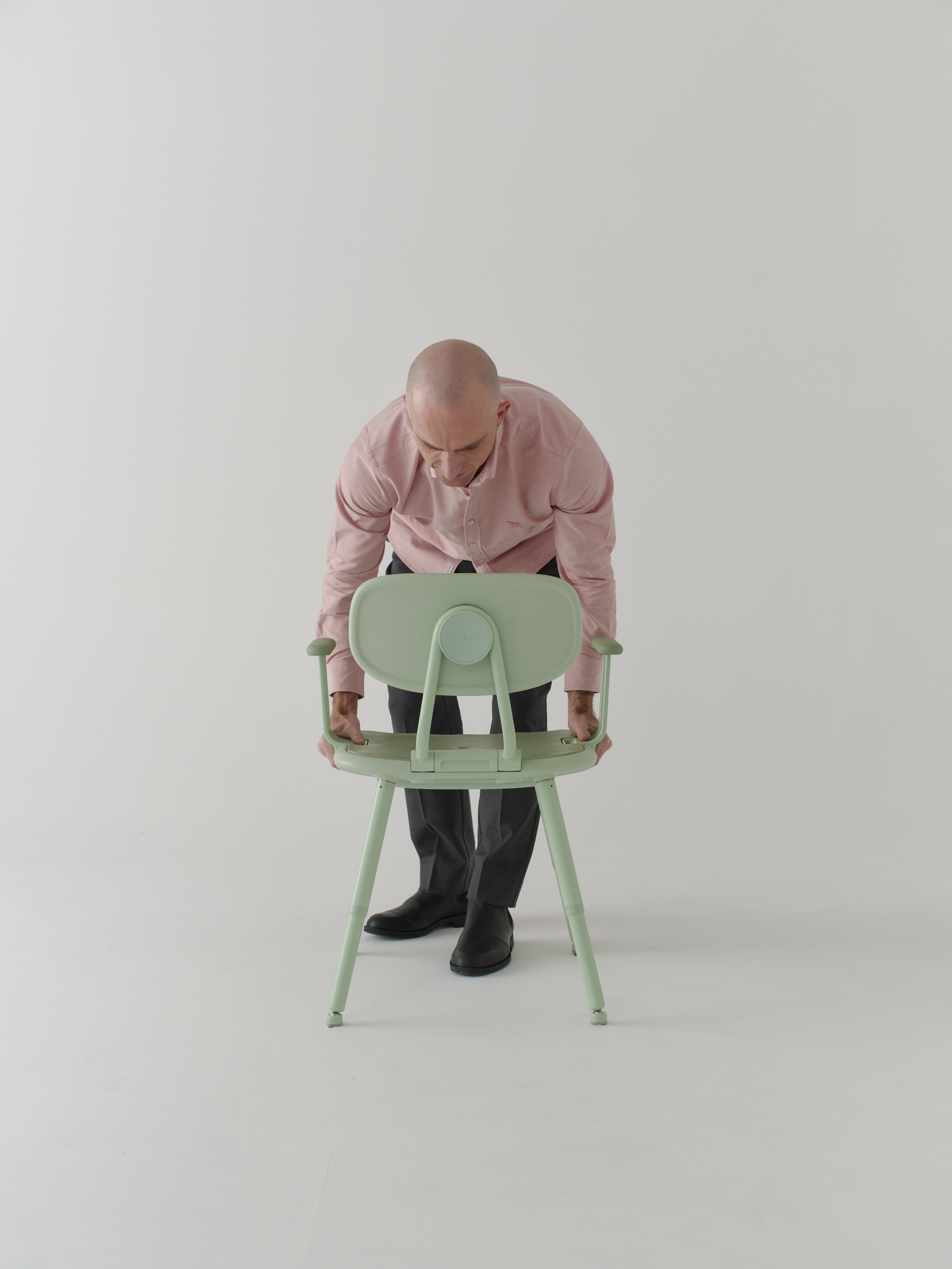 Man in pink shirt placing green chair on the ground