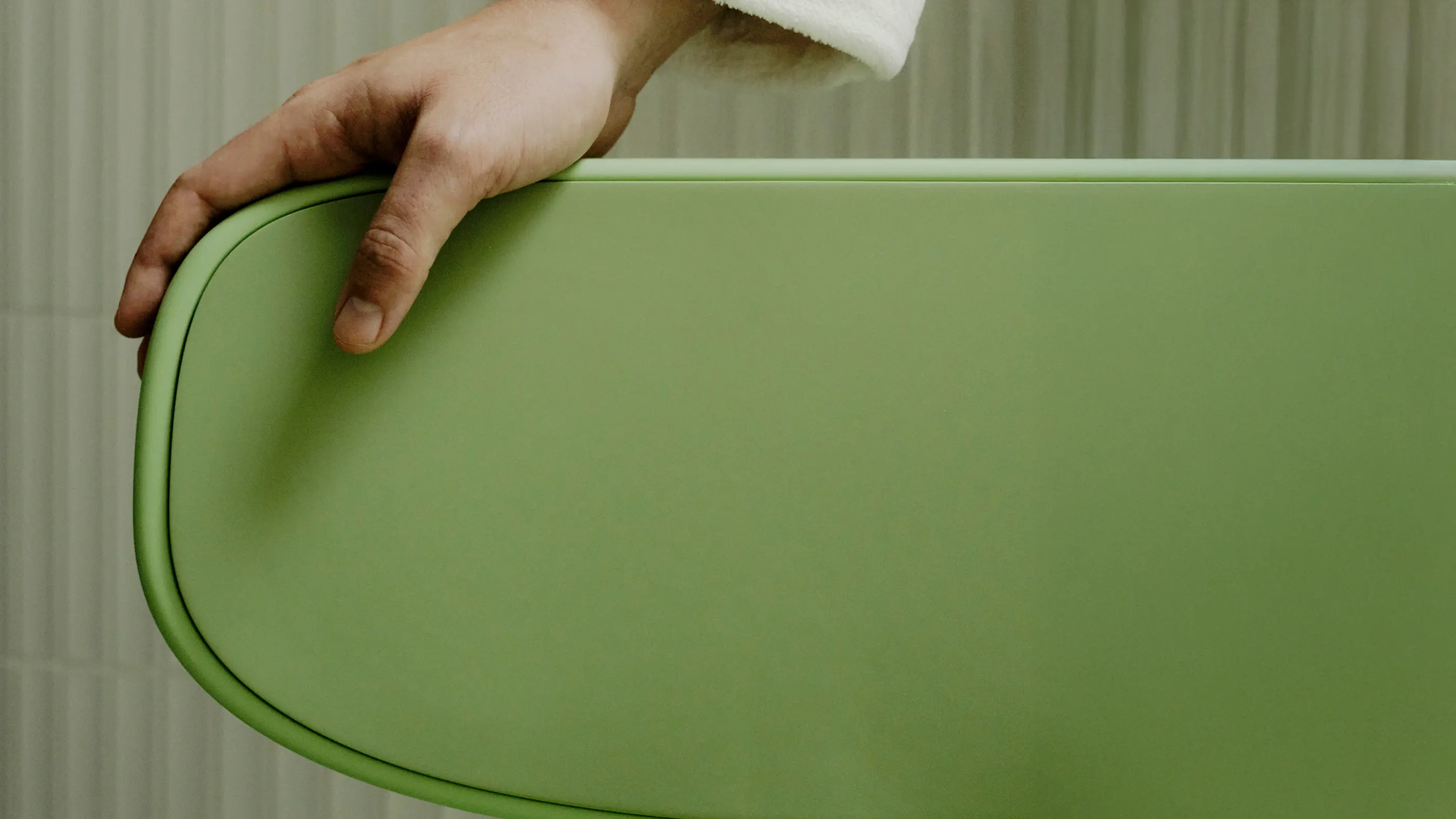 A hand rests on the oasis shower chair backrest