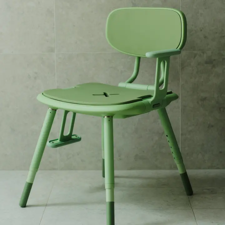 A pastel green Oasis shower chair is positioned with one adjustable armrest down