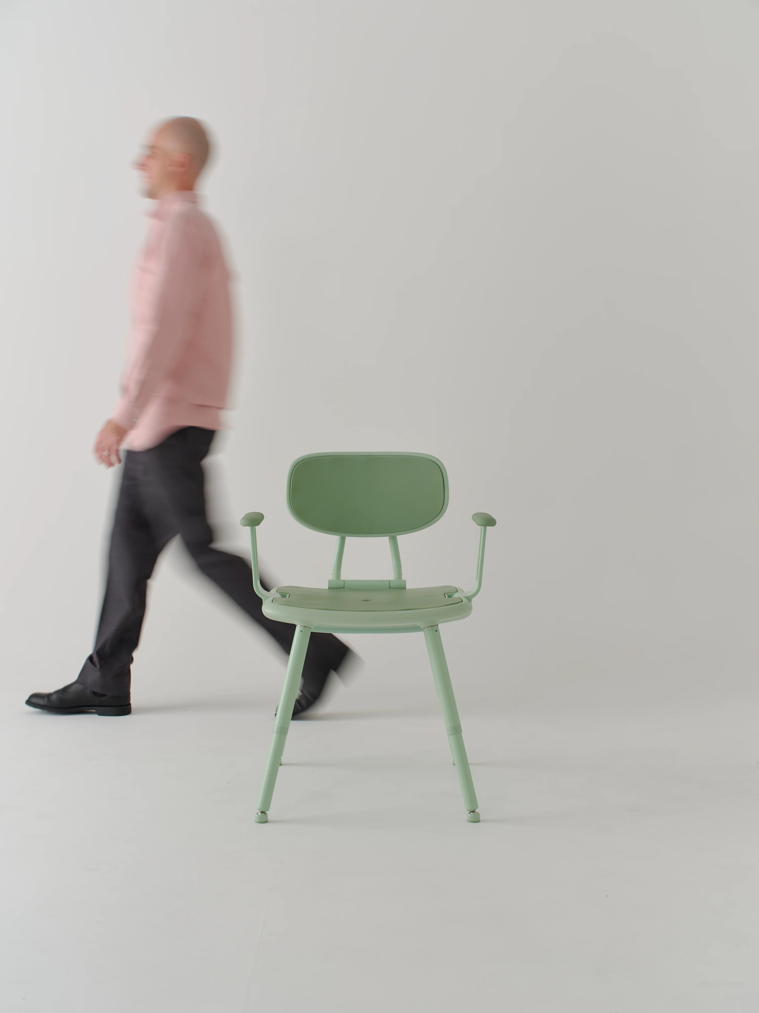 Man in pink shirt walks behind green oasis shower chair