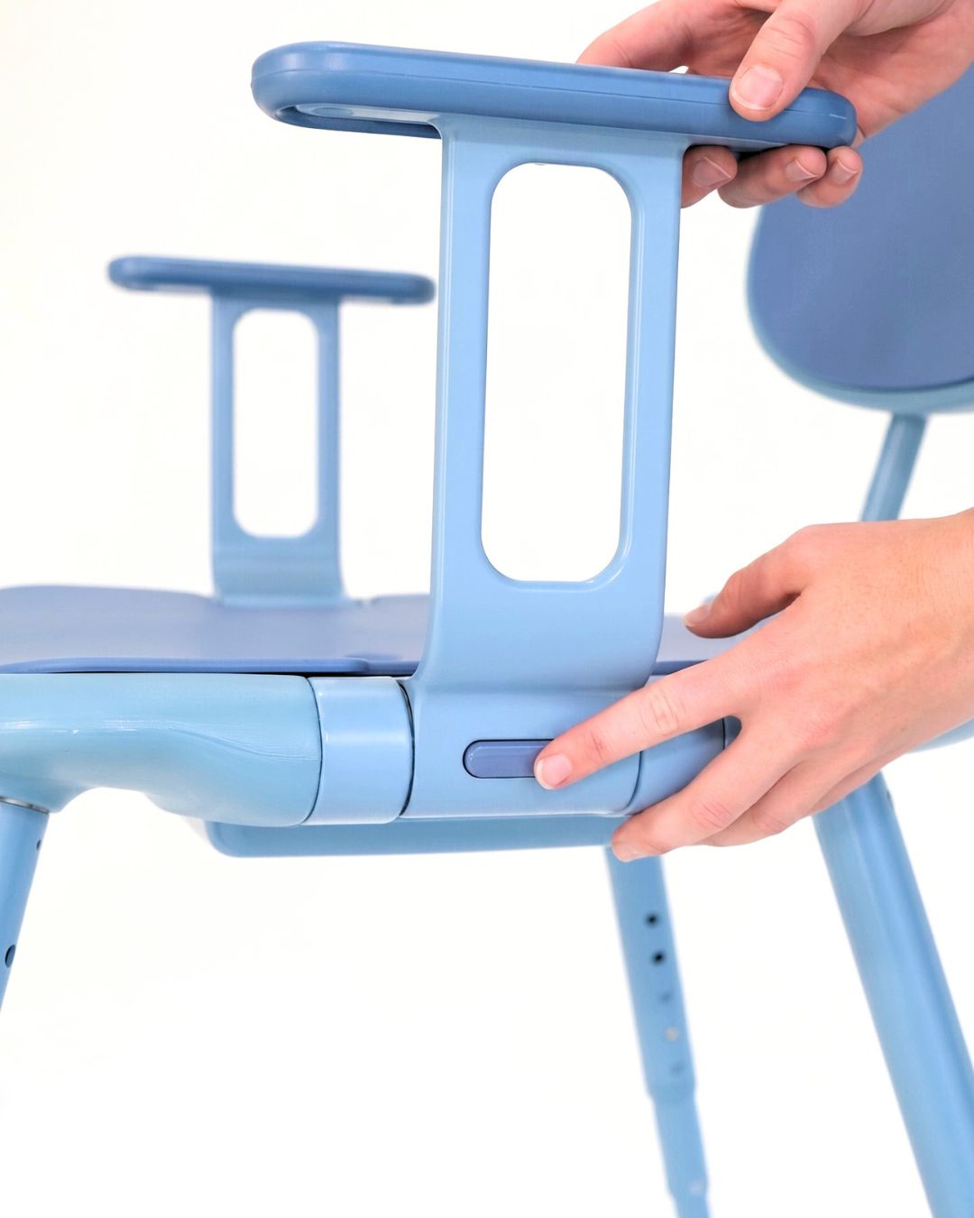 A hand pressing the Oasis Shower Chair armrest button.
