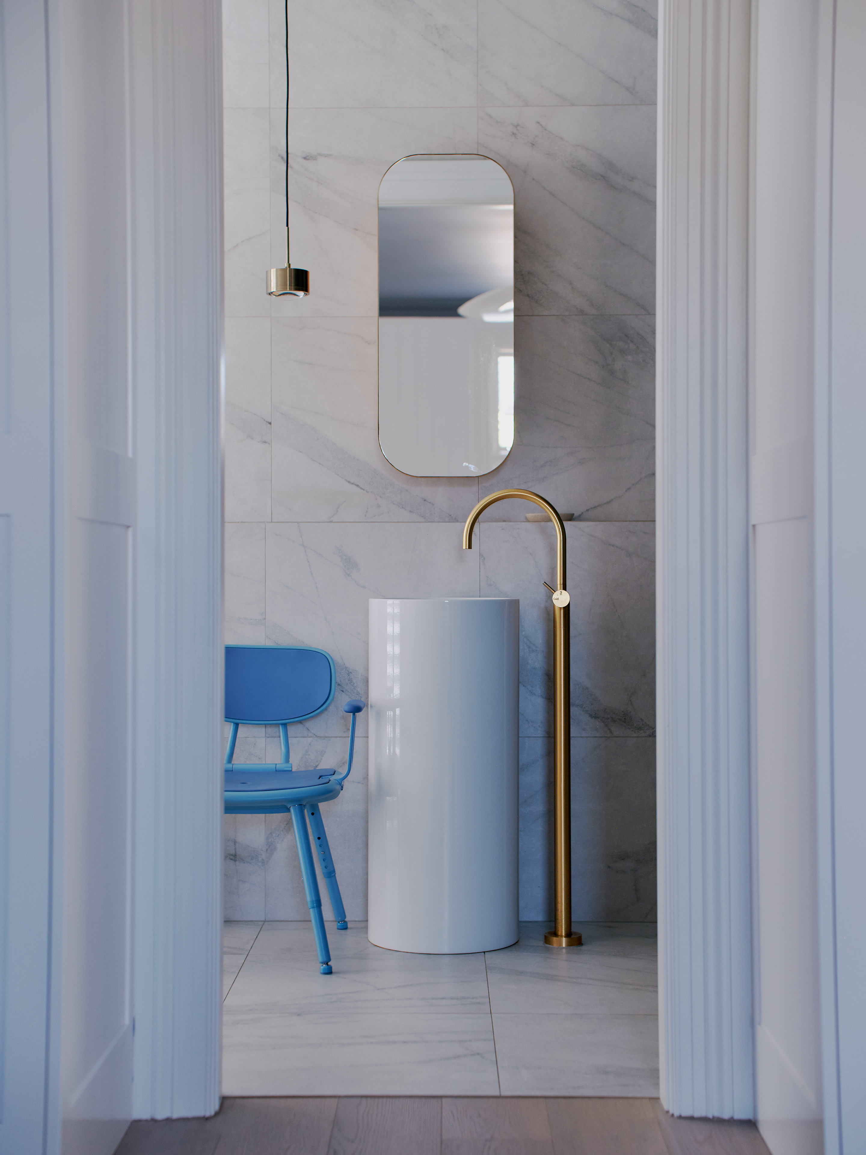 The Blue Oasis Shower Chair sits in a marble bathroom.